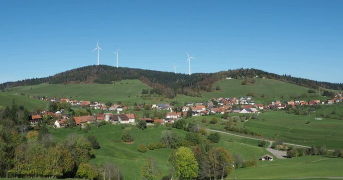 Black Forest landscapes in Southern Germany. Gersbach, village in forested mountains, slopes and hills with green pastures surrounded by the massif of Rohrenkopf und its wind turbines
