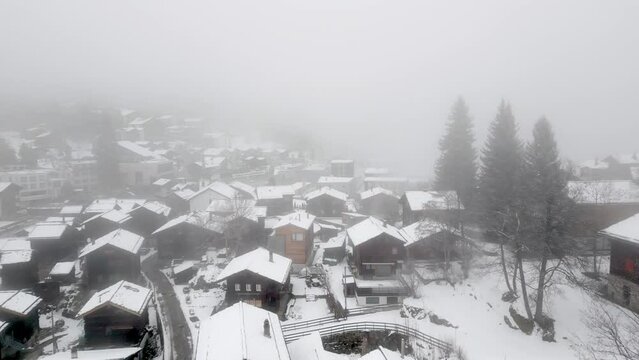 Snowy landscape with snowy cottages in the Swiss Alps. The village of Blatten near Belalp in fog and snow