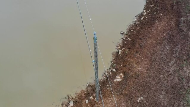 Aerial orbit of a wooden electrical distribution structure with ceramic insulators and cotter keys right next to a cow pond in rural Frankfort Kentucky. 4k