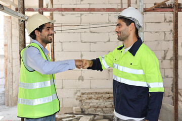 Fototapeta na wymiar Two technician civil engineer or specialist inspector making fist bumping celebrate successful together completed deal commitment at Industrial building site. Construction concept