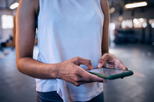Woman, hands or phone typing in gym for workout management app, fitness subscription or exercise healthcare data. Zoom, sports athlete or personal trainer on mobile technology for social media blog