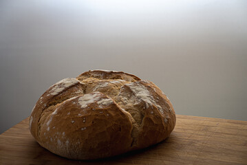 Bread loaf on a wooden board and white background. Homemade bread. Peasant bread isolated on white background. Home cooking.