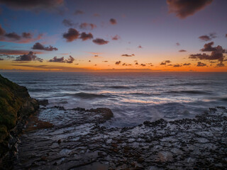 Obraz premium Surfs up sunrise at the seaside with scattered clouds