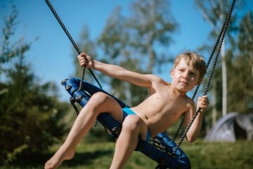 cute little boy having fun on a swing at playground