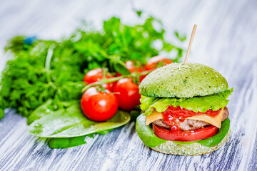 Burger with green bun with artificial meat, fresh vegetables on wooden background. Vegetarian food 