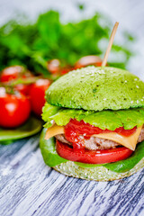 Closeup green burger with artificial meat, fresh vegetables on wooden background. Vegetarian food 