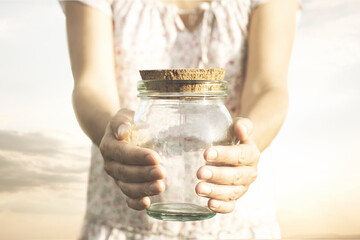 woman showing an empty glass jar that she holds in her hands, concept of economic crisis, savings,...