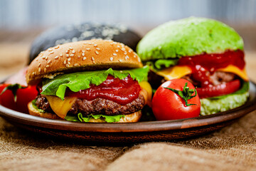 Closeup of set of three color homemade burgers with marble beef on rustic table. selective focus 