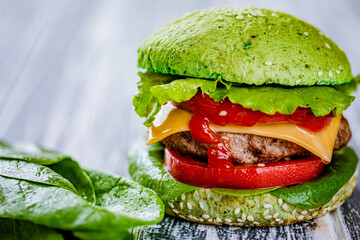 Closeup green burger with artificial meat, fresh greenery on wooden background. Vegetarian food 