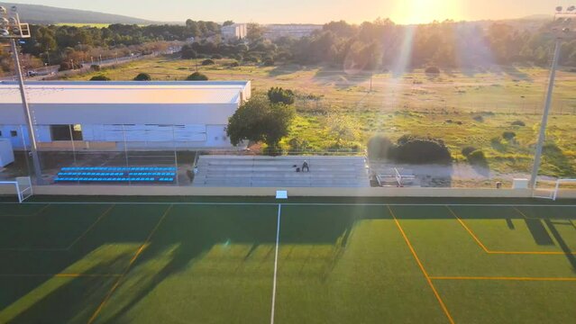 Backwards revealing drone shot of a football field during golden hour in Santa Ponsa, Mallorca, Spain.