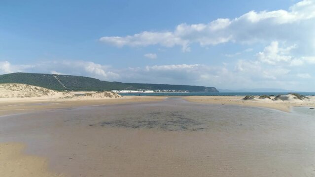 Flying over a vast sand beach in Los Canos de Meca in Spanish bay in Summer time