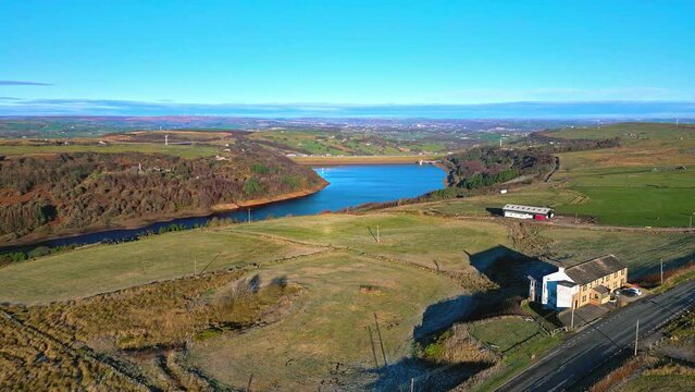 Winter aerial footage scene of  Scammonden Reservoir with the M62 motorway bridge. West Yorkshire, England. With blue water roads, and farm buildings.