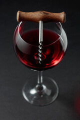 Glass of red wine and corkscrew.