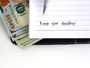 pen and cash dollars money on white copy space background and text written notebook KEEP YOUR DEADLINE, to finish writing project on time