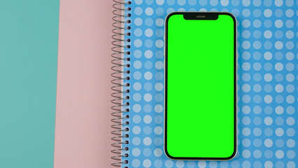 Mobile phone with empty blank green screen flat lay, Smartphone isolated on blue and pink colour background