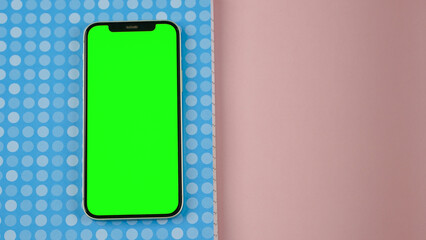Mobile phone with empty blank green screen flat lay, Smartphone isolated on blue and pink colour background
