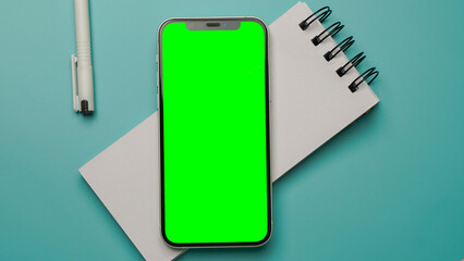 Mobile phone with empty blank green screen flat lay, Smartphone isolated on blue colour background