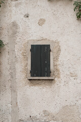 Fototapeta na wymiar Rustic Italian architecture. Ancient building facade with bush, wooden window and neutral beige wall
