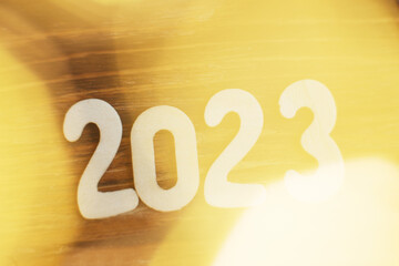 wooden number 2023 on christmas beautifull shiny gold background. sparkle festive blurred bokeh