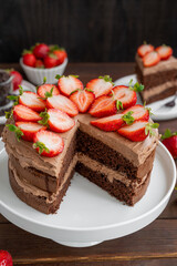 Naked chocolate cake with cream and fresh strawberries on top. Rustic style. Selective focus. Copy space.