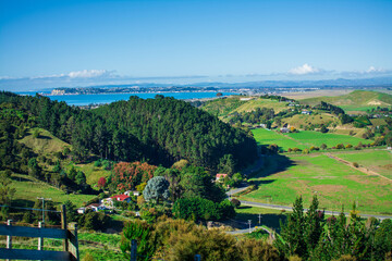 Breathtaking view over farmhouse amongst lush meadows by green hills. Beautiful autumn day at a seaside region of Hawkes Bay, New Zealand