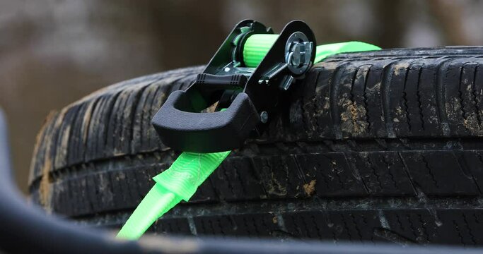 Lime green ratchet strap holding down a spare tire on an Overlanding SUV roof rack on a dreary winter moody day. 4k