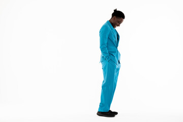 Side view of handsome dark skinned man model standing on whitebackground in studio isolated wearing funny hairstyle looking down smiling laughing.