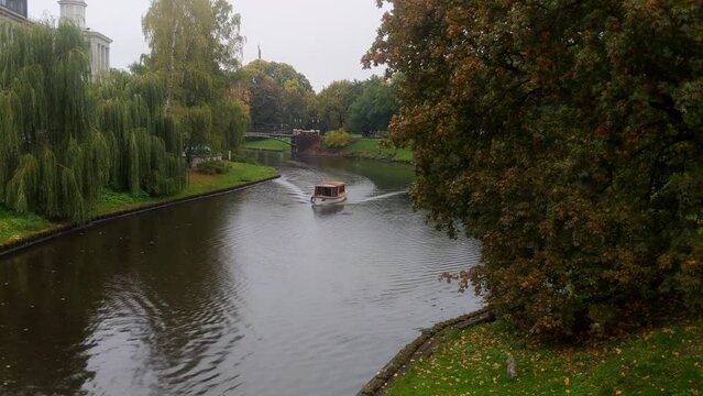 Sightseeing tourist boat on Riga canal in rainy autumn day, Latvia