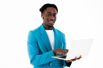 Portrait of modern young african american man sitting on floor in white studio isolated photo shooting working time holding laptop wearing modern earphones speaking with coleagues by video link.