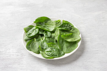 Plate with fresh spinach leaves on a light gray background. delicious healthy food