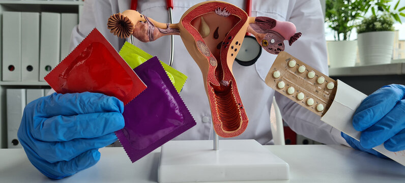 Female doctor holds condom for prevention of AIDS and birth control pills