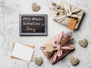 Zero waste Valentine's Day concept and mock up. Eco-friendly gift cloth wrapping in Furoshiki style,craft paper envelope,empty gift or greetings card,chalkboard with Zero Waste Valentine's Day letters