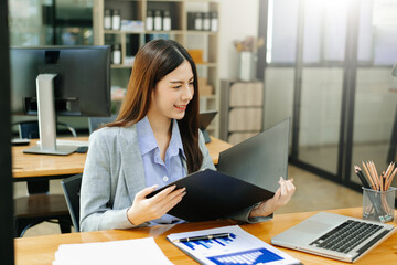Asian businesswoman working in the office with working notepad, tablet and laptop documents .
