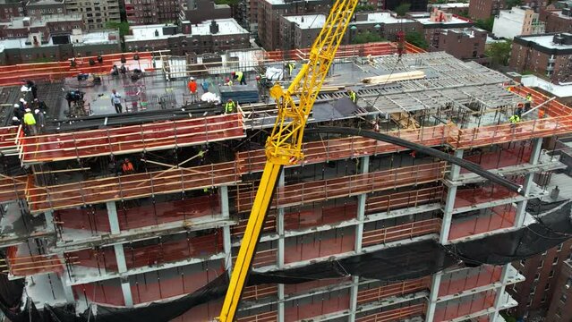 Aerial view following a crane lifting rebar to contractors on top of a building