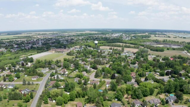 Aerial view of quaint, suburban town of Embrun, Ontario, Canada. Quiet neighborhoods, green trees, school with track and wide flat horizon.