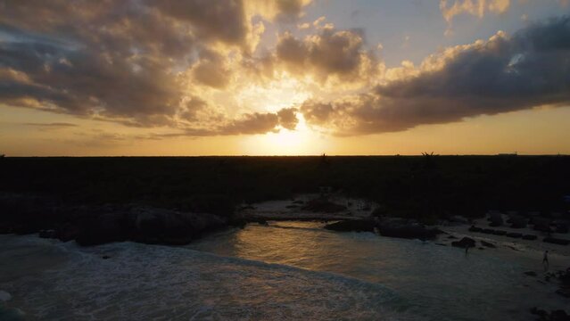 Aerial view of a dramatic sunset sky with a cinematic reveal of the beach on the Caribbean sea in Gitano Tulum