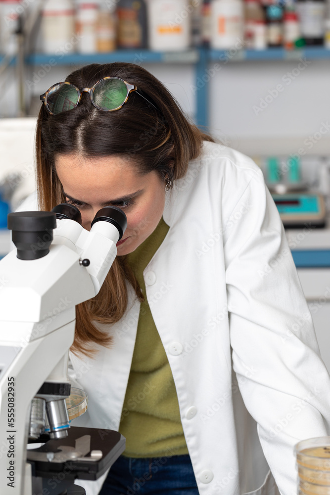 Wall mural Young scientist under a microscope in a scientific laboratory