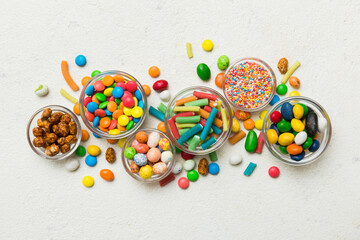 different colored round candy in bowl and jars. Top view of large variety sweets and candies with copy space