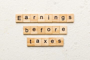 Earnings Before Taxes word written on wood block. abbreviation EBT text on cement table for your...