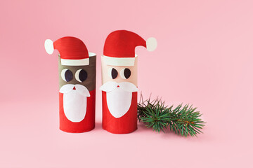 Christmas decoration for winter season. Holiday easy DIY craft idea for kids. Toilet paper roll tube toy. Santa snowman deer on pink background. eco-friendly, reuse, recycle handmade minimal concept
