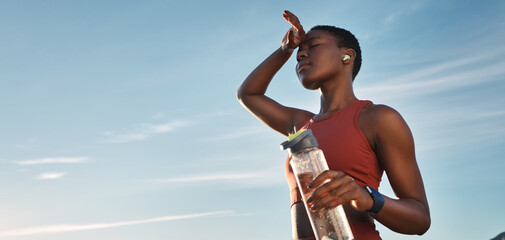 Water bottle, tired and black woman on break after running, exercise or cardio workout with low...
