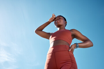 Black woman, tired or sweating in fitness workout or training exercise on blue sky background in healthcare wellness. Low angle, runner or sports athlete exhausted, fatigue or marathon challenge done