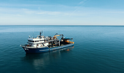 Fishing boat aerial view from drone on sea surface. Fishing and seafood industry.