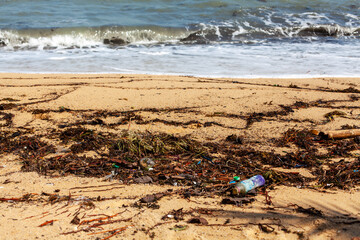Fototapeta na wymiar Garbage on sea sand beach, unsorted rubbish, plastic bags, glass bottle, metal can, trash, refuse pile, litter, dirty ocean water, environmental pollution, ecological problem concept, waste management