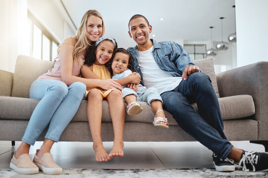 Interracial, portrait and family on sofa, love and bonding on weekend, break and smile together. Multiracial, man and woman with daughters, kids and in living room for quality time, happy and couch. - Powered by Adobe