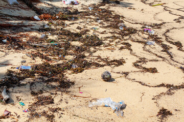 Garbage on sea sand beach, unsorted rubbish, plastic bags, glass bottle, metal can, trash, refuse...