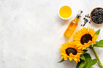 Blooming yellow sunflowers with cooking oil and black seeds, top view
