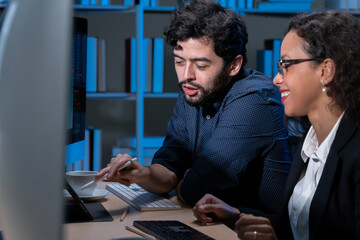 business men and women who are working hard Working late into the night to complete tasks according to set goals The two of them looked at the company's financial graph attentively.