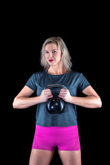 portrait of a beautiful young fitness woman exercising with kettlebell in studio with black background