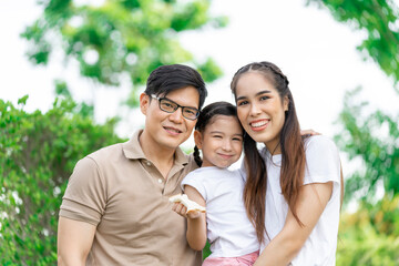 Young Asian parents doing activities eating and playing with their daughter in the front yard during the holidays happily.